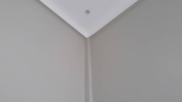 Peindre une chambre : Peinture murale tendue et ligne nette entre mur et plafond – GLR Peinture Nantes Peindre une chambre : Angle de mur gris et plafond blanc peint avec rigueur
