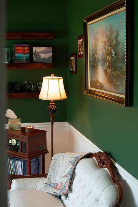 Salon cosy à Nantes avec murs verts foncés et boiseries blanches